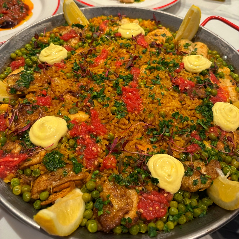 Spanish fiesta paella dish served with lemon slices in a metal pan.