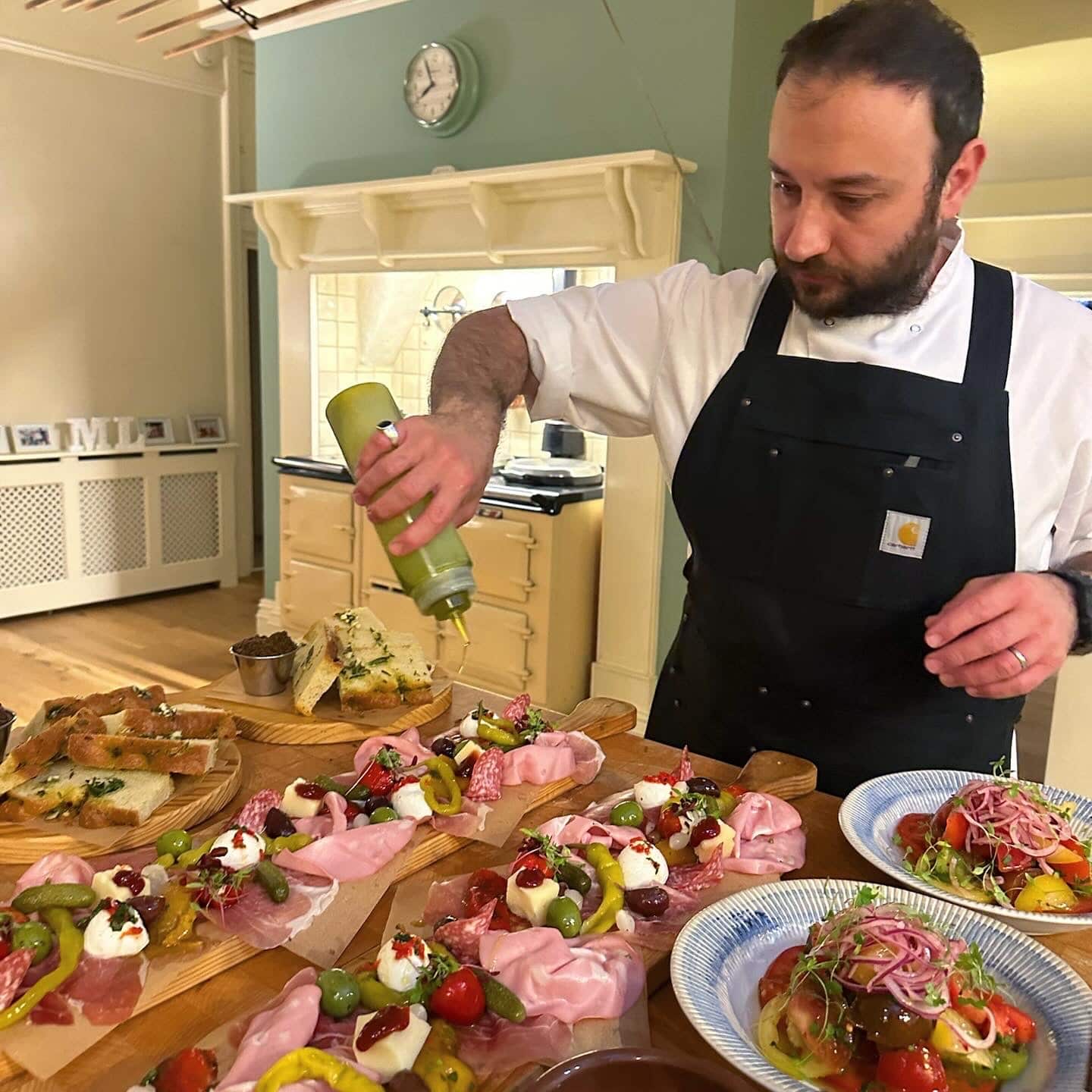 Chef assembling charcuterie boards with cured meats and seasoning.