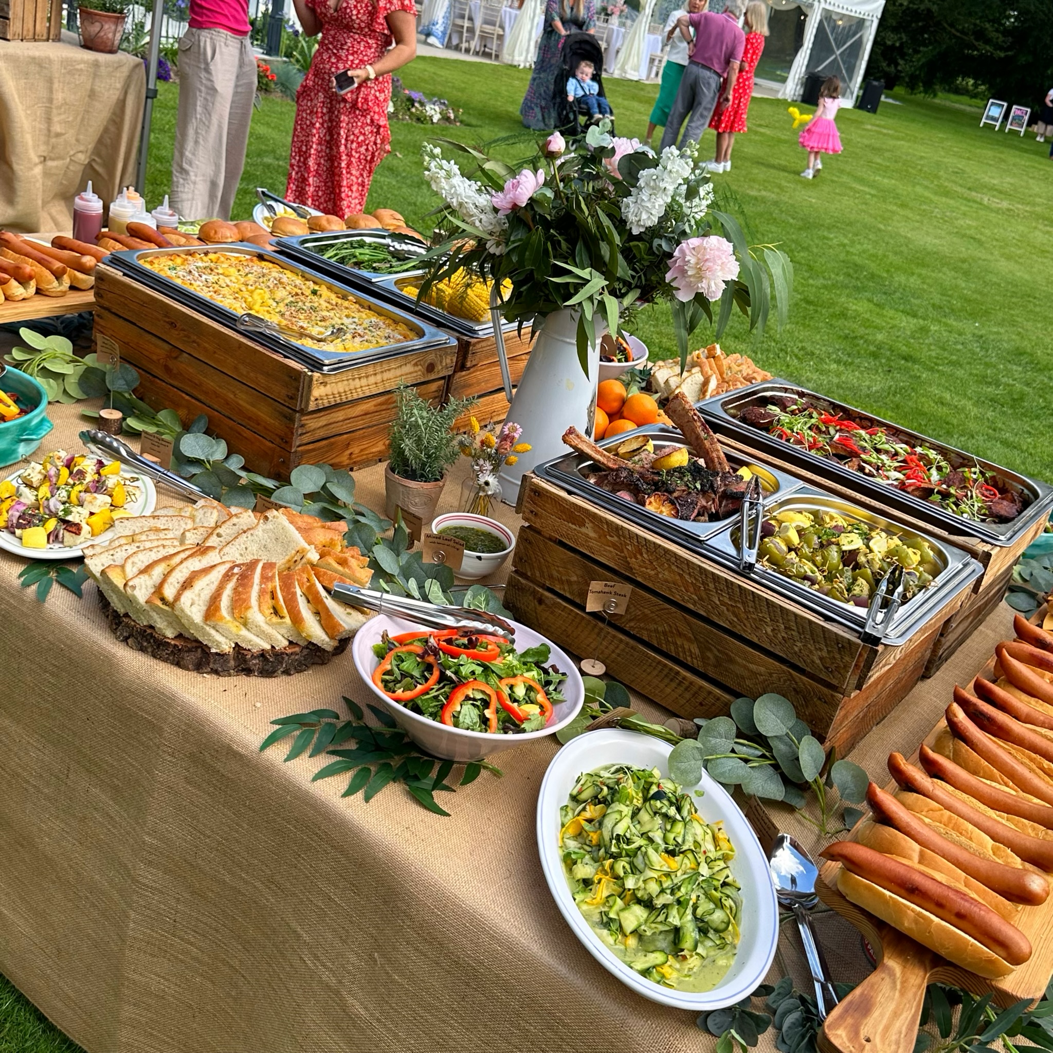 BBQ outdoor buffet table featuring grilled meats, vegetables, and decorations.